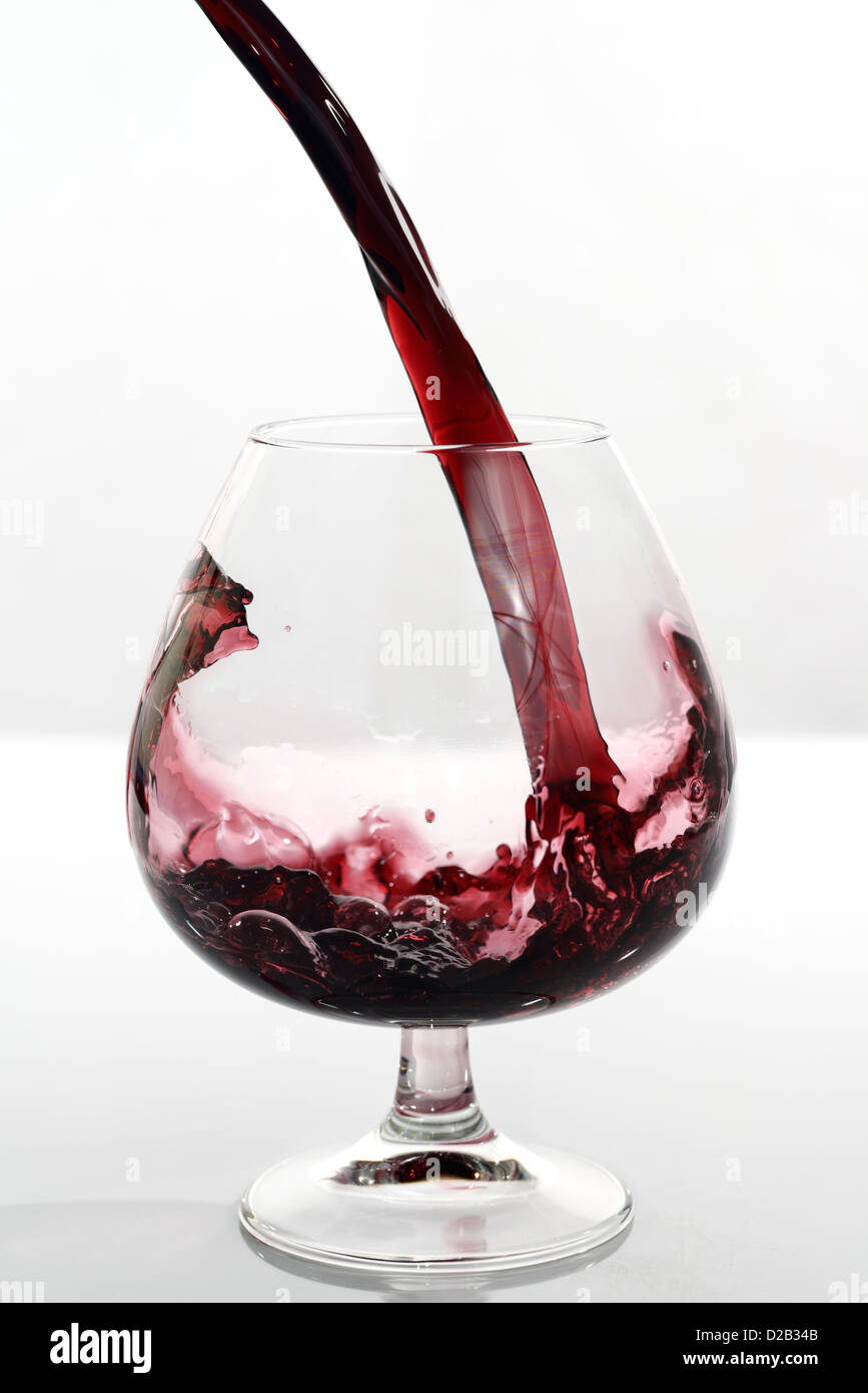 Frozen motion of port pouring into a glass snifter on a white background Stock Photo