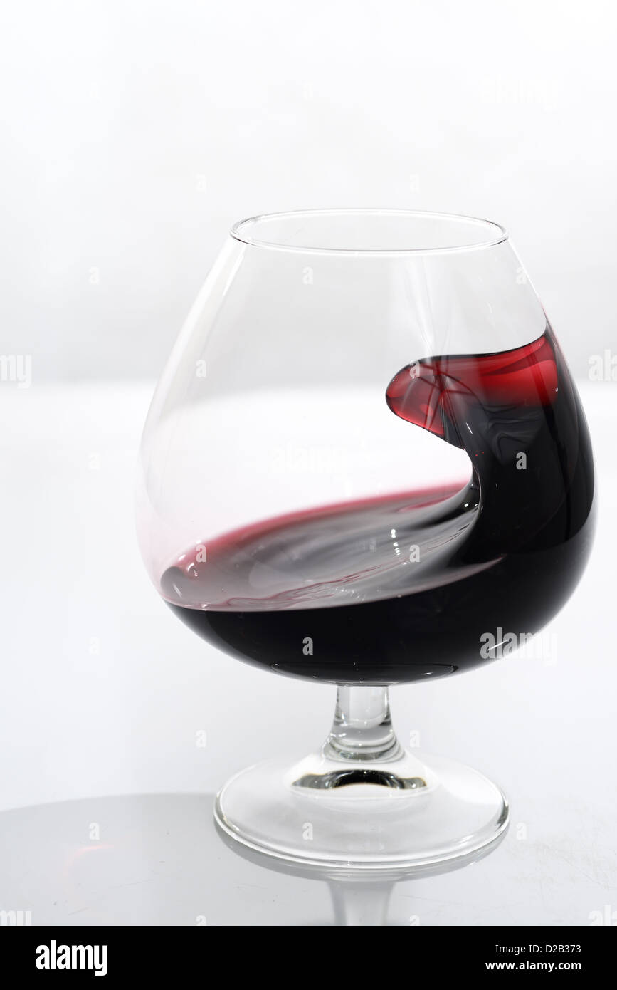 Odd shape of port swirling in a glass snifter on white background Stock