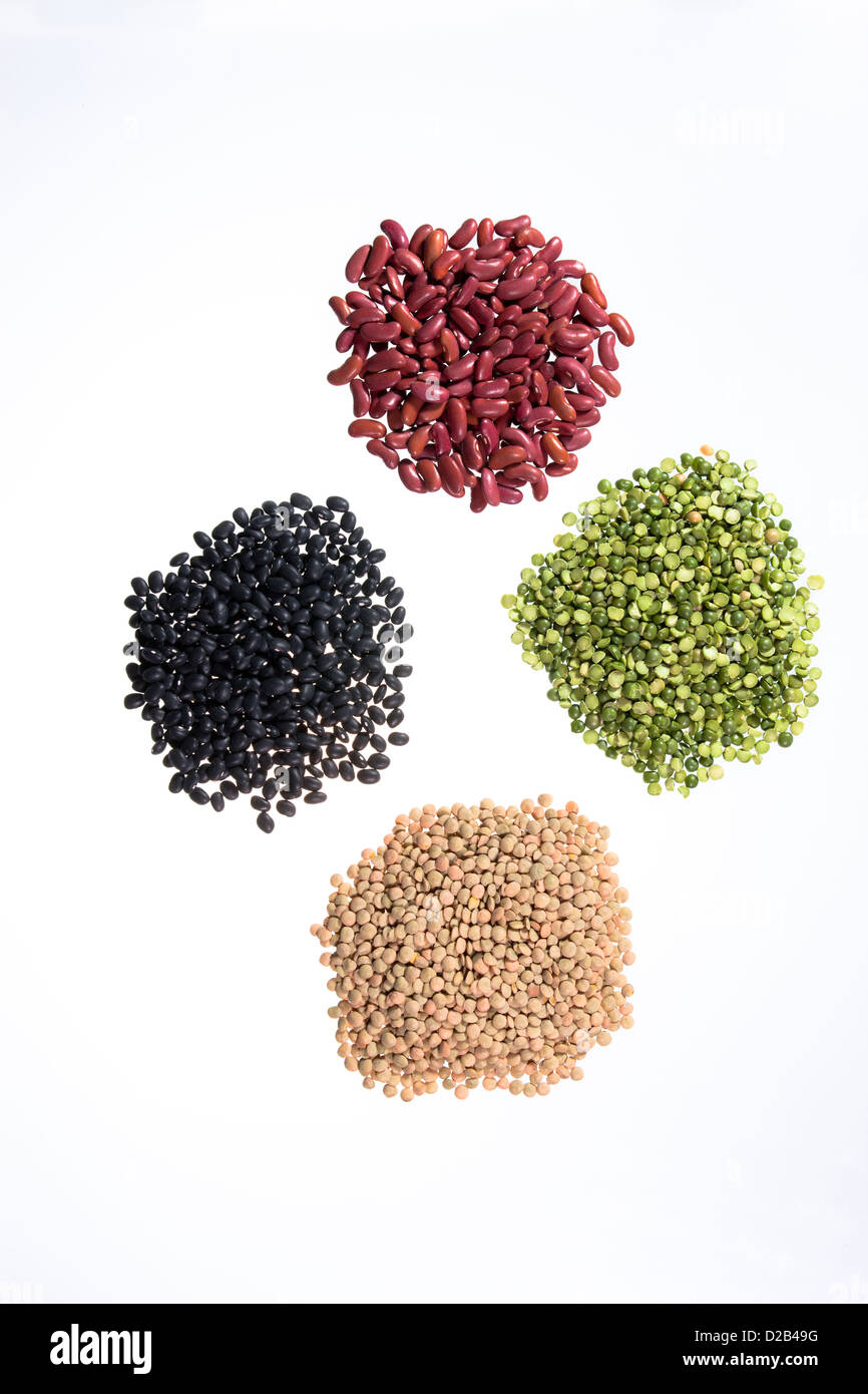Four piles of dried peas, lentils, black beans, and kidney beans on white background. Stock Photo