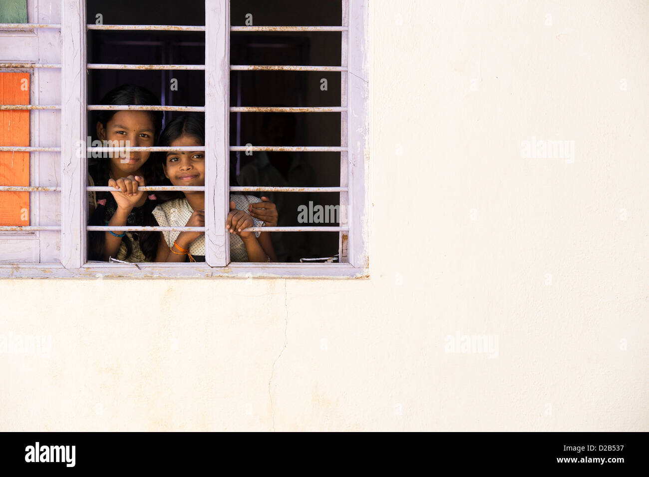 Young Indian village girls looking through window bars in an Indian ...