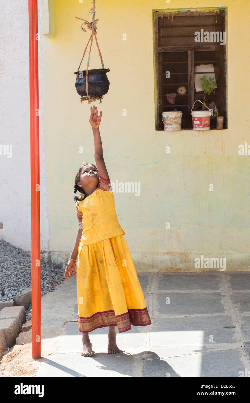 Indian village girl reaching up to stored cooked food outside her home. Andhra Pradesh, India Stock Photo