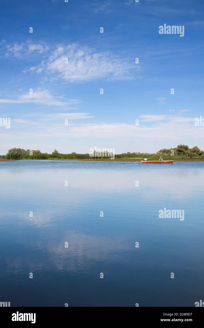 A single fishing boat on a calm and serene Tisza Lake in Eastern Hungary Stock Photo