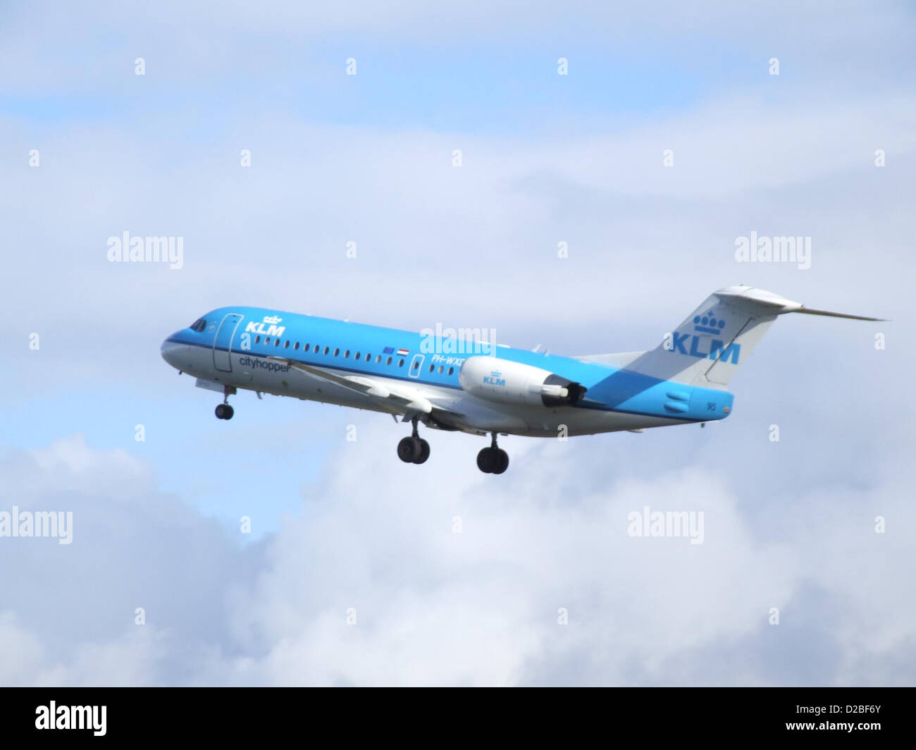 The Fokker 70 is a regional jet operated by KLM Cityhopper, known for its compact size and efficiency. The aircraft, PH-WXD, is seen parked at an airport, ready for its next flight, featuring a sleek design and powerful engines typical of regional airliners. Stock Photo