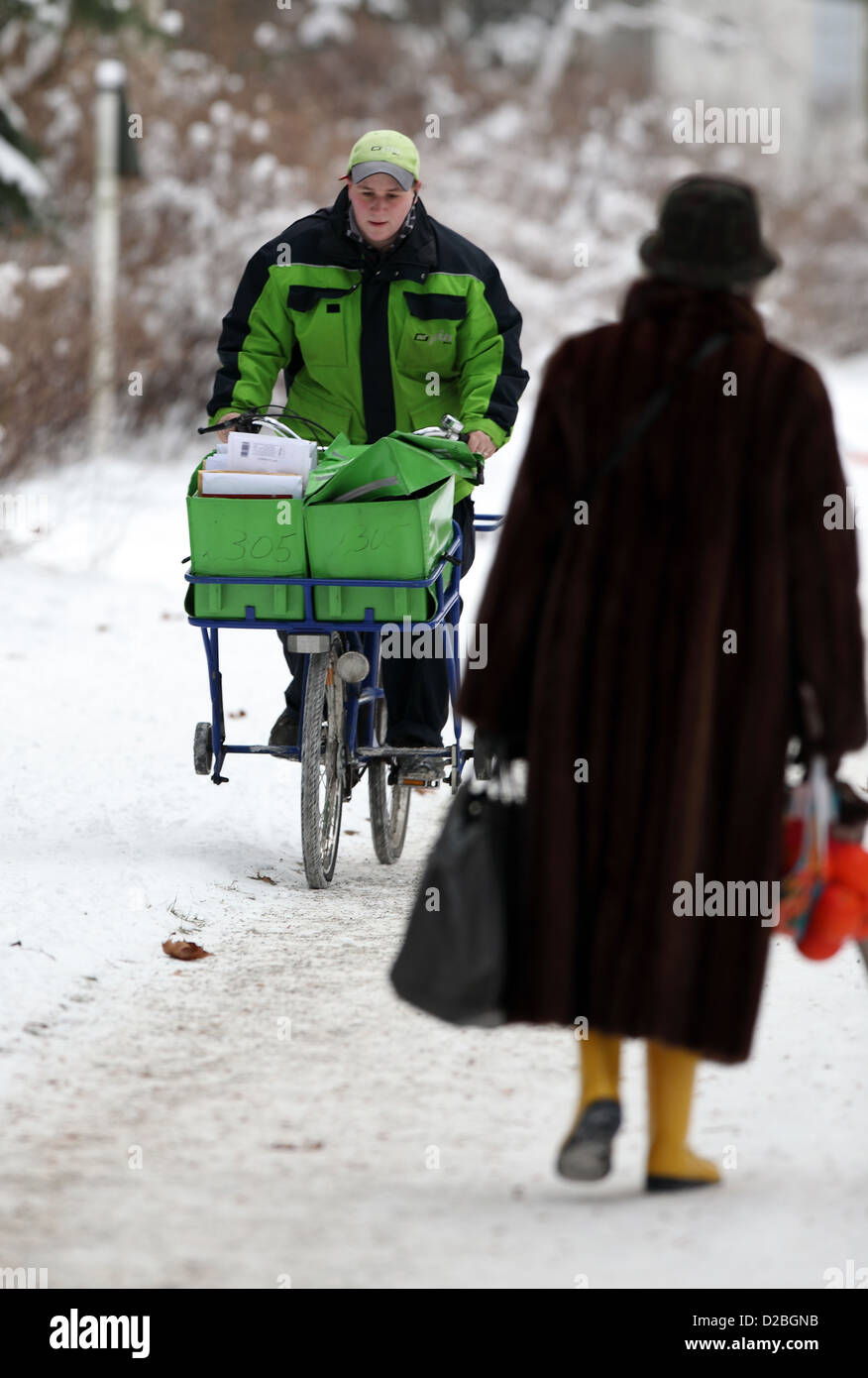 Berlin, Germany, the postman PIN AG is proceeding bike along a snowy sidewalk Stock Photo