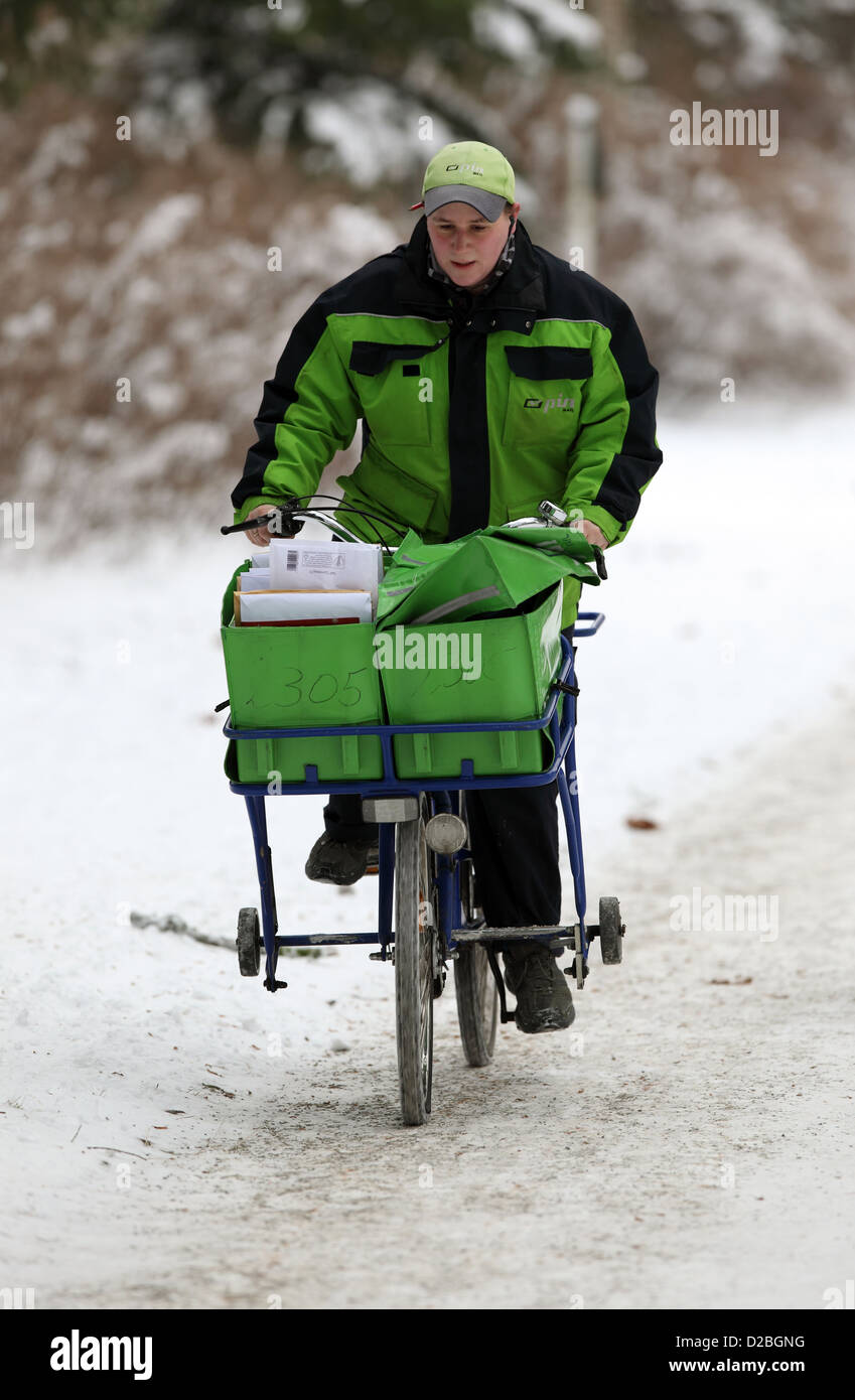 Berlin, Germany, the postman PIN AG is proceeding bike along a snowy sidewalk Stock Photo