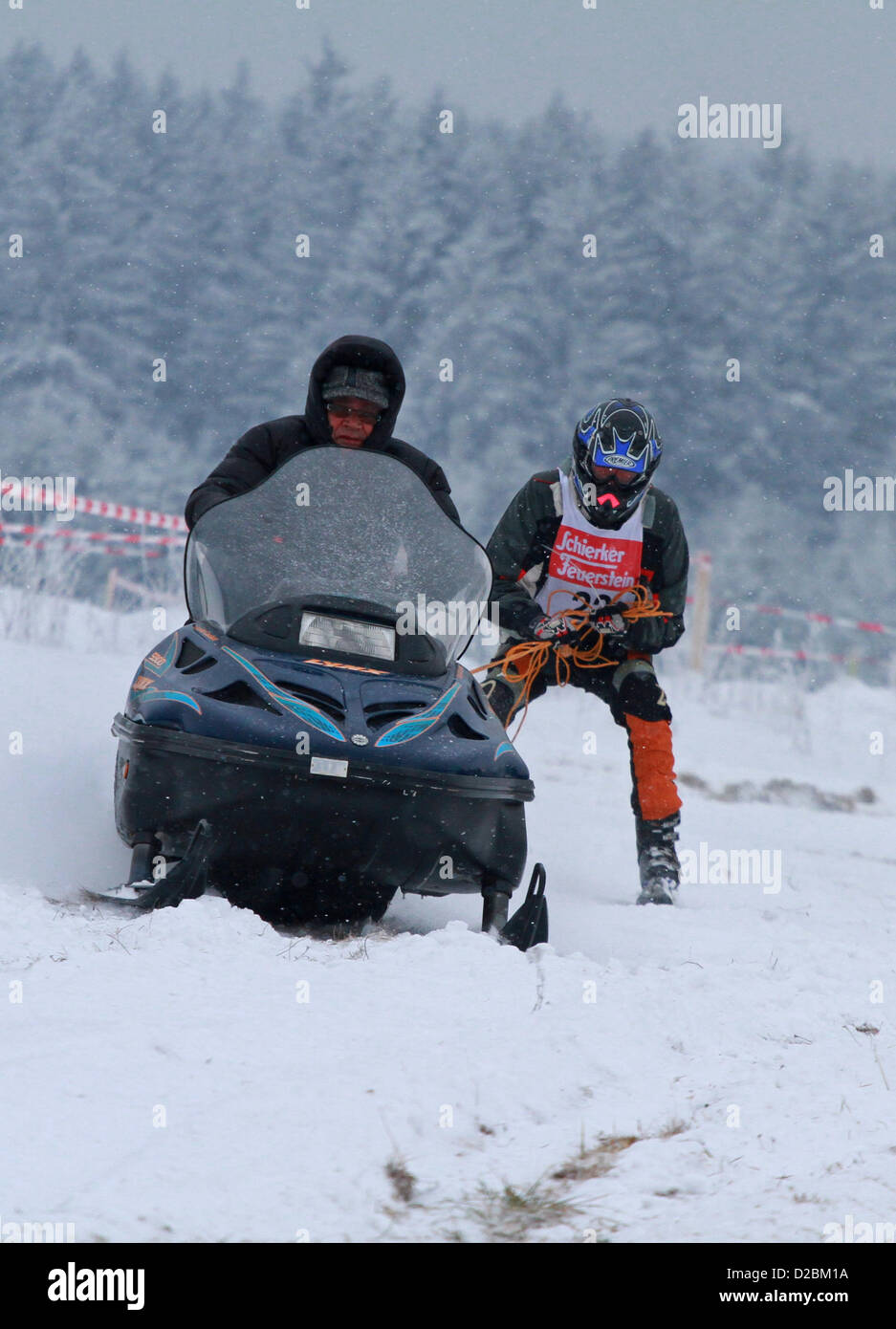 Juergen Kurkiwicz pulls a snow boarder with a motor sleigh across an obstacle course in Elend, Germany, 19 January 2013. More than 100 contestants participate in this curious race which is based on a Scandinavian winter sports concept. Skiers are being pulled across an obstacle course either with animals or motorised vehicles. Photo: Matthias Bein Stock Photo