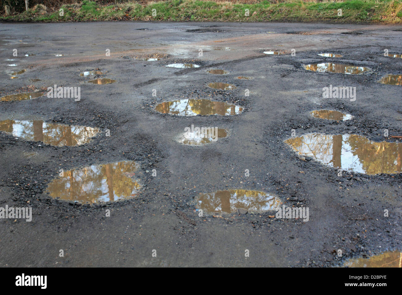 Water filled pot holes in a woodland car park. Surrey England UK Stock