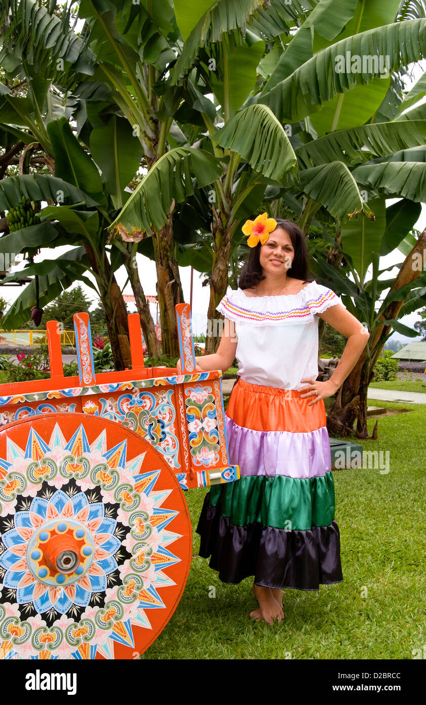 Costa Rican Woman In Traditional Dress Next To Traditional Carriage In And Around Costa Rica. Stock Photo