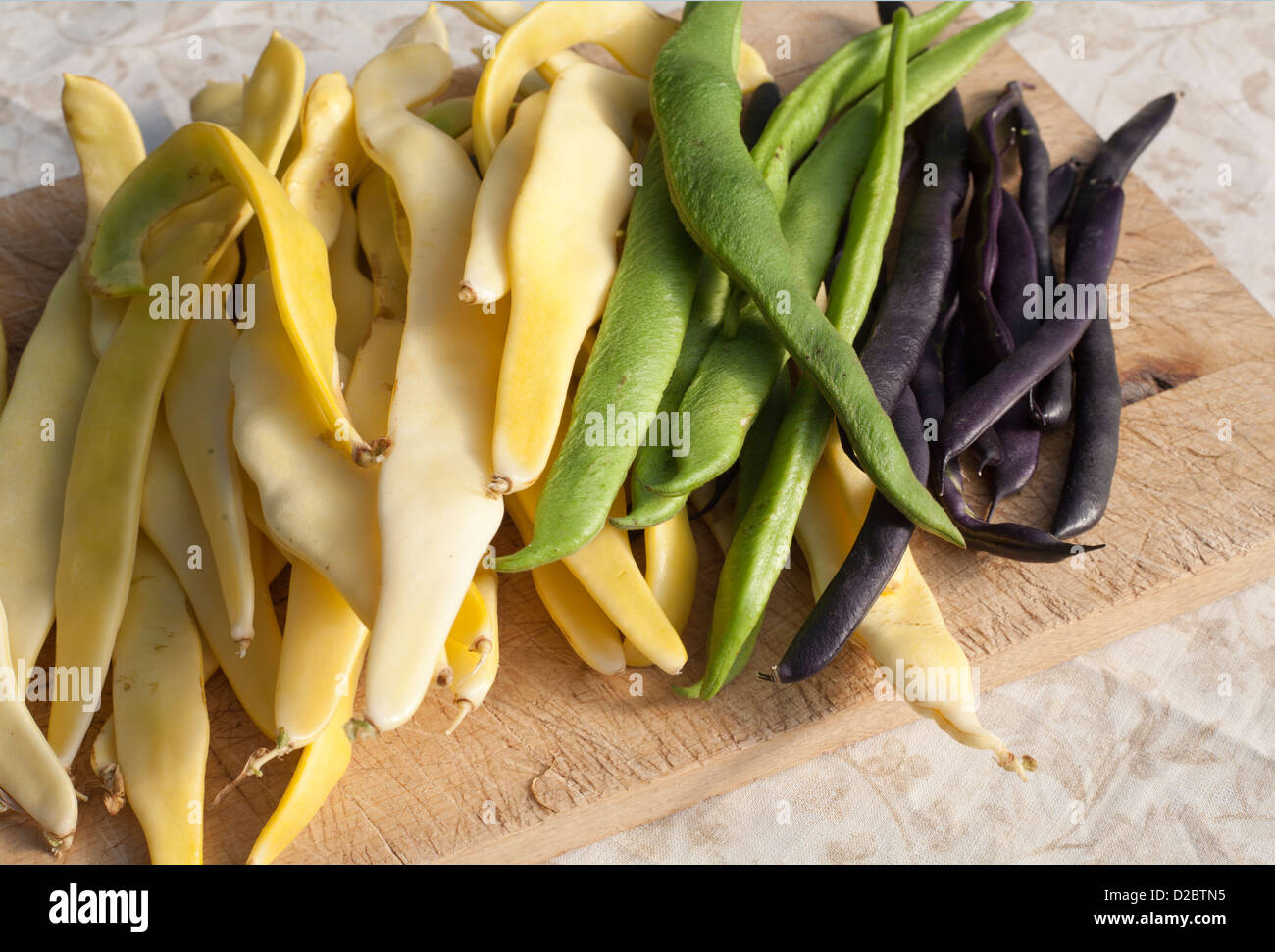 Organic runner beans in green,black and cream on a chopping board Stock Photo