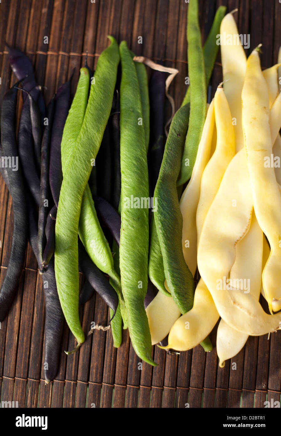 Organic runner beans in green,black and cream on a bamboo mat Stock