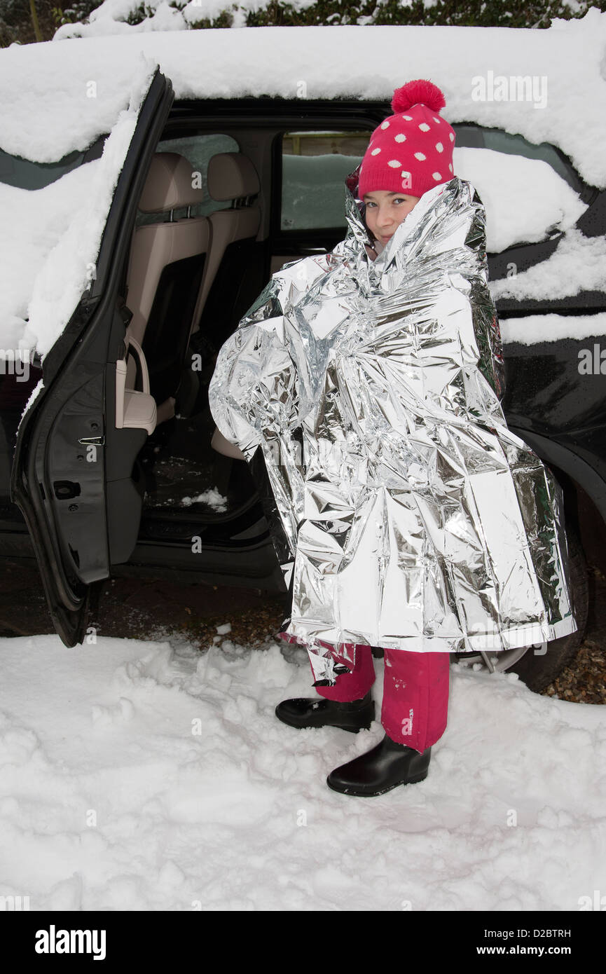 Young child keeping warm with a foil blanket wrapped around her. Car