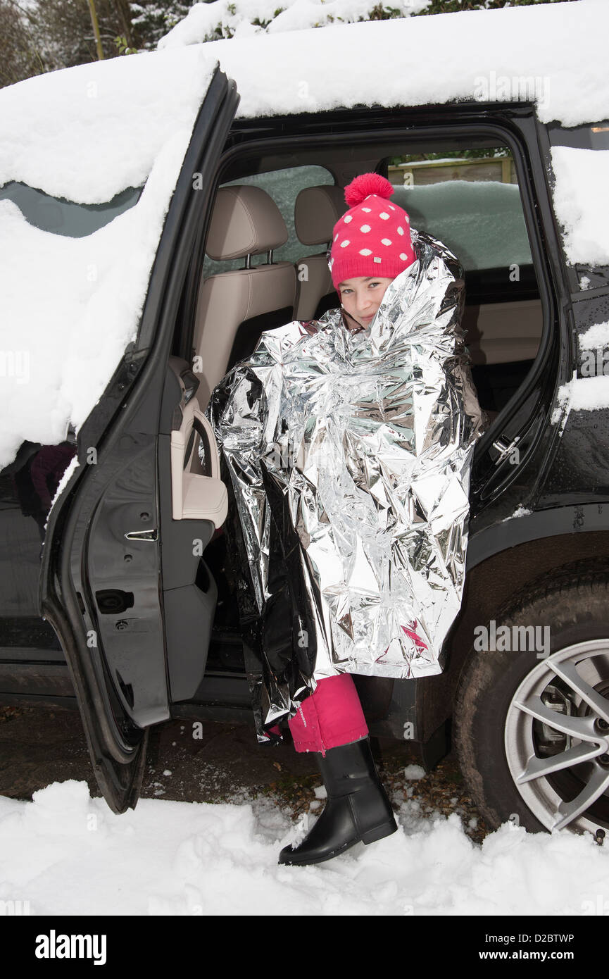 Young child keeping warm with a foil blanket wrapped around her. Car