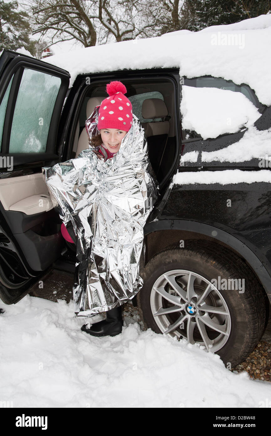Young child keeping warm with a foil blanket wrapped around her. Car