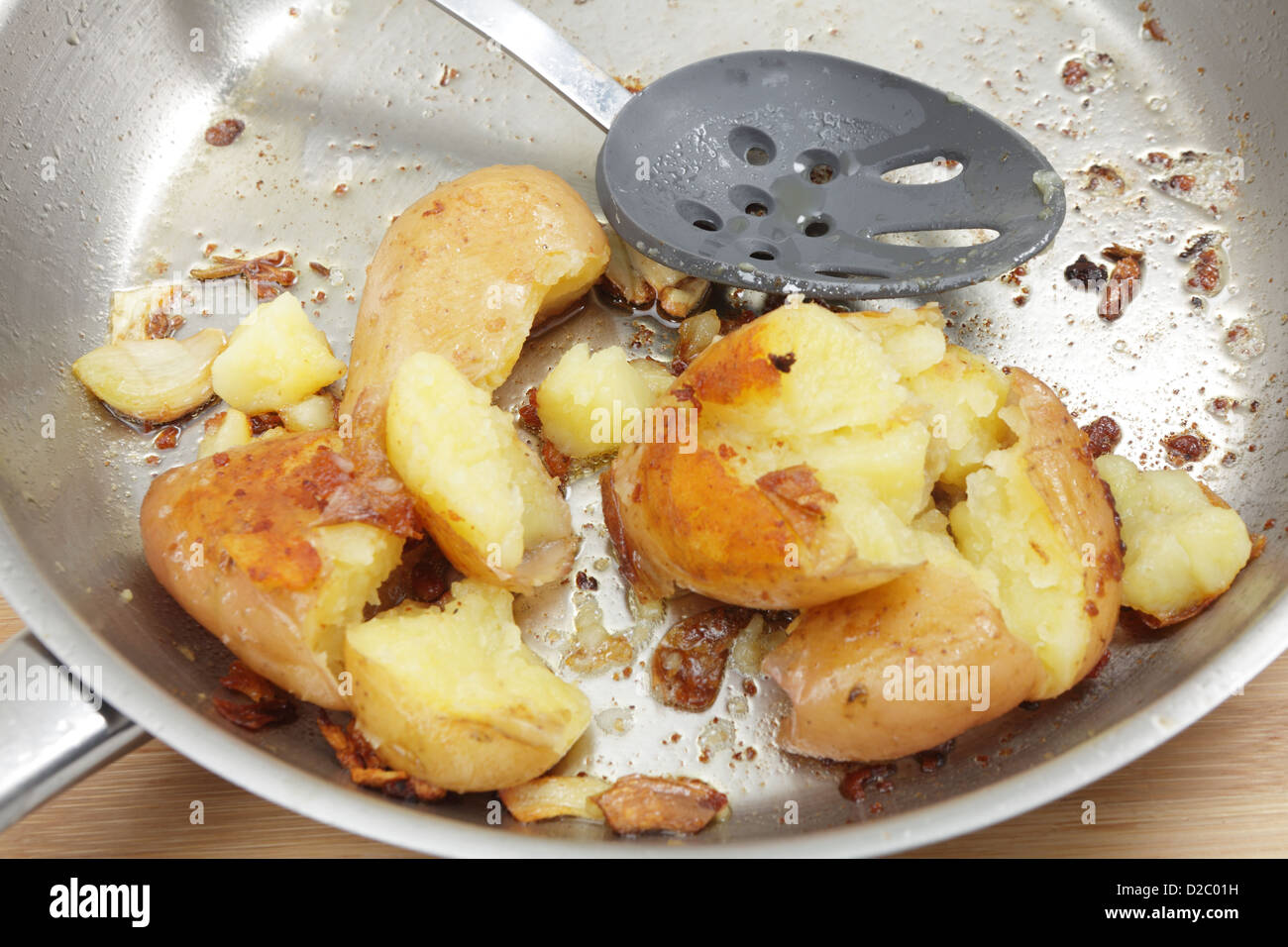 A frying pan with crushed potatoes cooked in butter and olive oil with