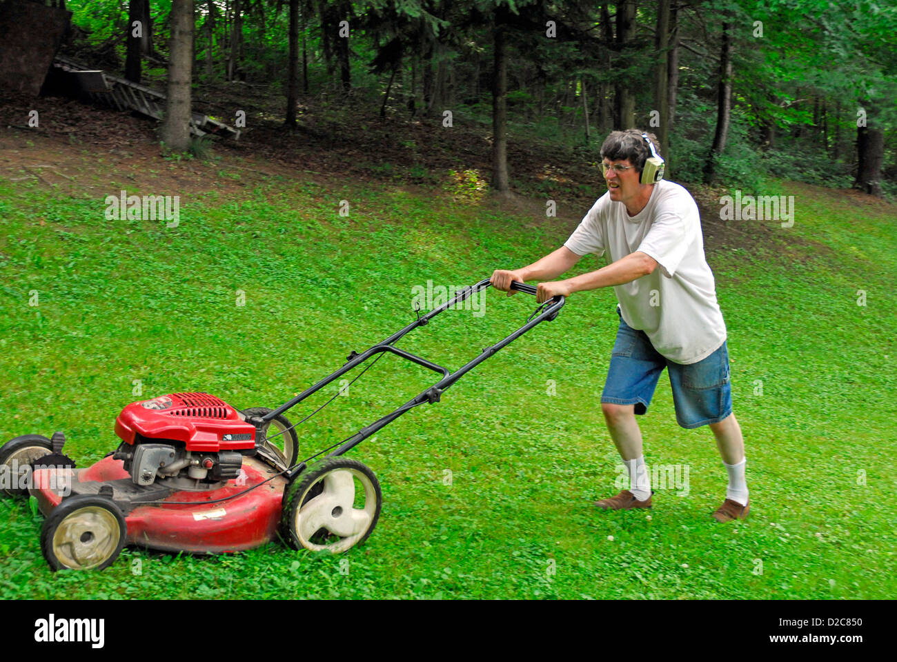 Man Mowing Lawn With Ear Protectors Stock Photo