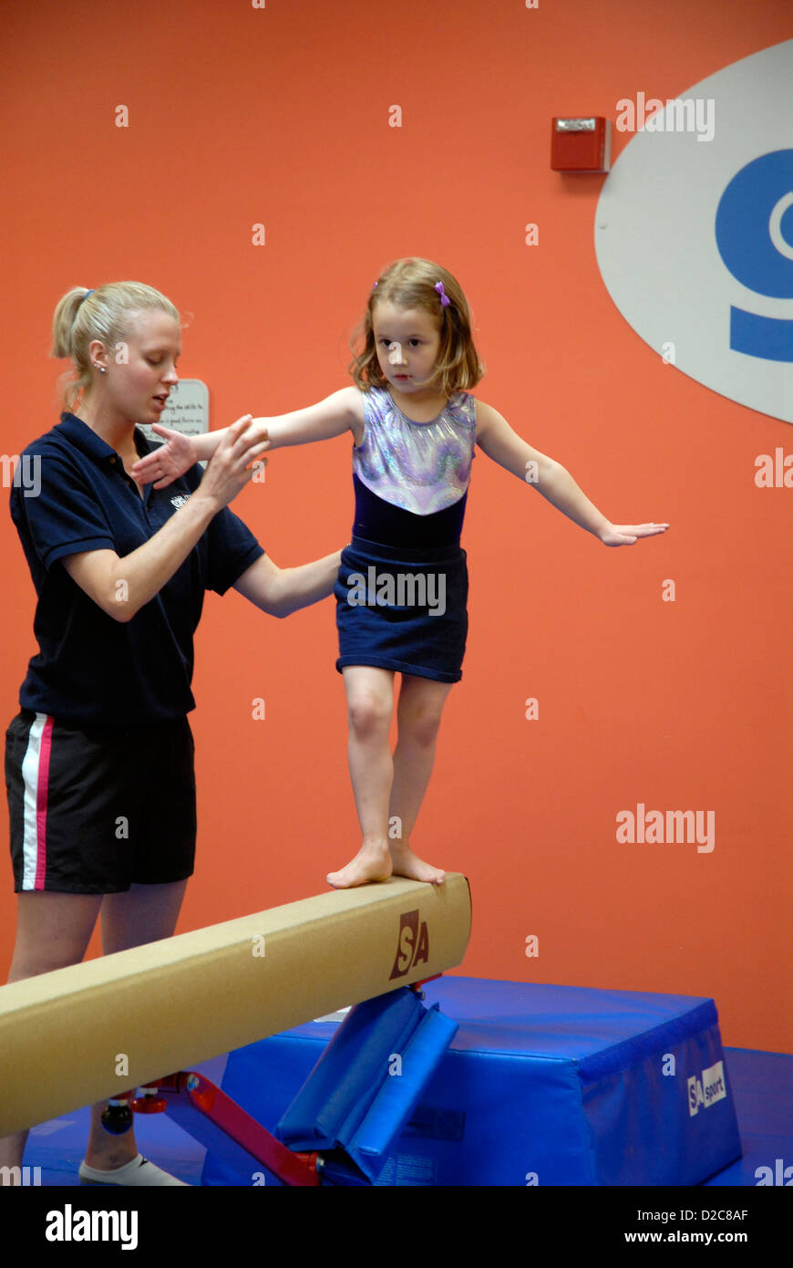 Gymnastics Class. Instructor Holding 4 1/2 Year Old Girl On Balance Beam Stock Photo