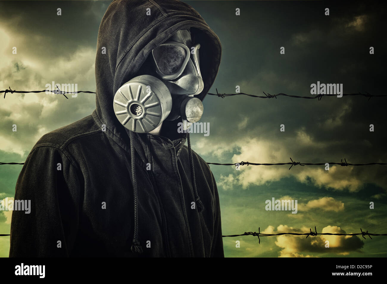 Man in dark clothes wearing a classic gas mask respirator in front of barb  wire fence Stock Photo - Alamy