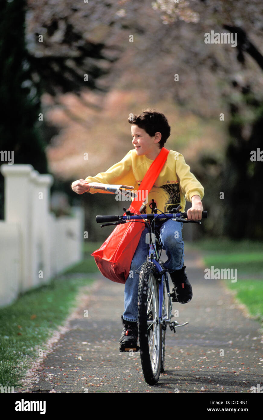 Boy On Bicycle Delivering Newspapers On Paper Route. Stock Photo