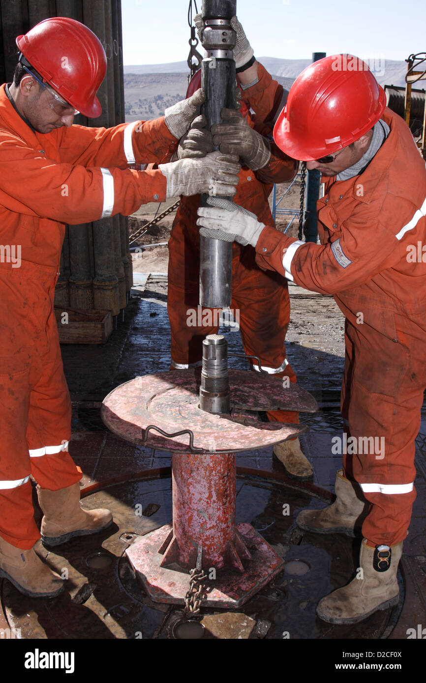 Onshore oil and gas exploration site with crewmen pulling out wire line tools after logging on rig platform Iraqi Kurdistan Stock Photo
