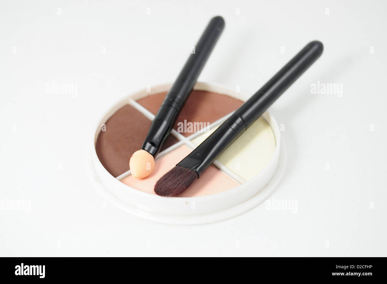 Set of four eyeshadows and makeup brushes on white background Stock Photo