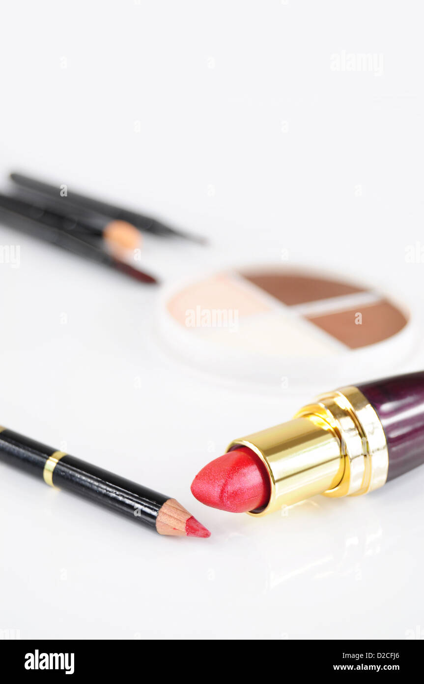 Closeup of red lipstick and pencil, eye-shadows and brushes in the background Stock Photo