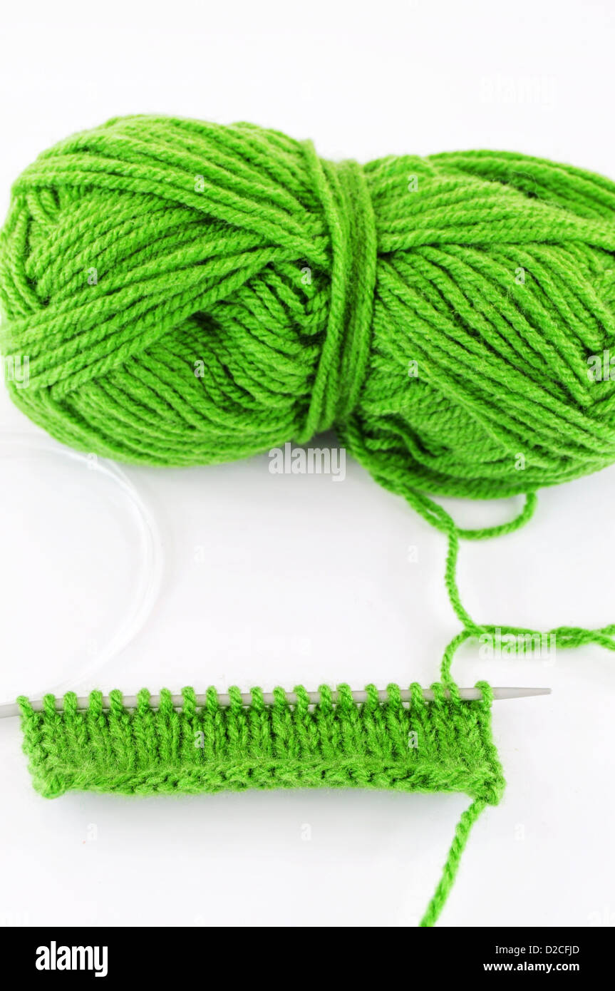 Green and yarn and needles and piece of knitting Stock Photo