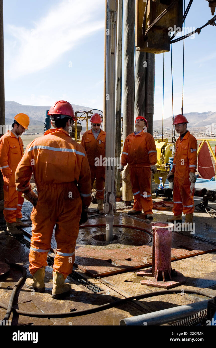 Onshore oil and gas exploration site with crewmen pulling out wire line tools during logging on rig platform Iraqi Kurdistan Stock Photo