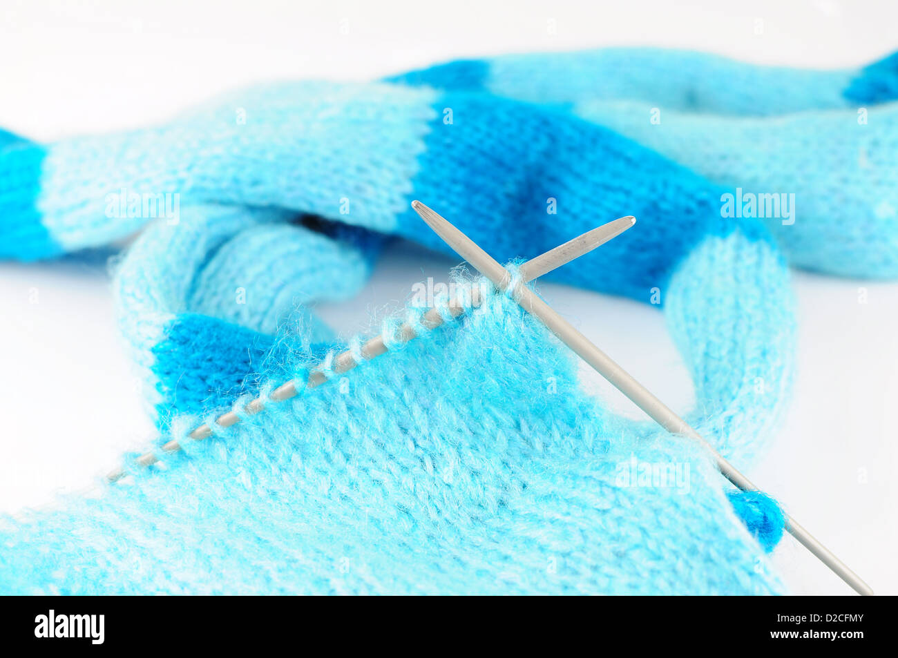 Needles knitting blue scarf on white background Stock Photo