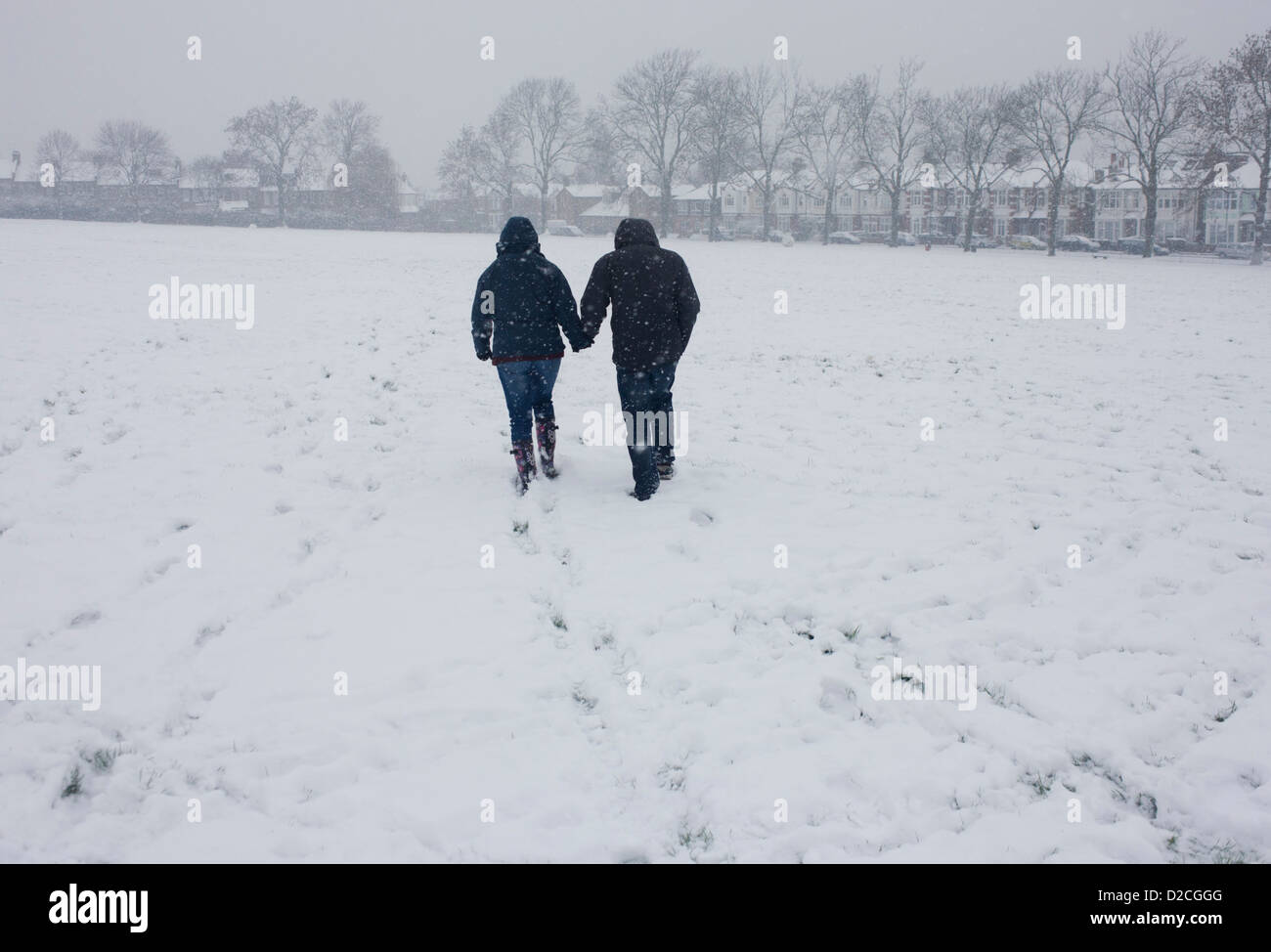 A couple walk hand in hand towards housing through snowbound public ...