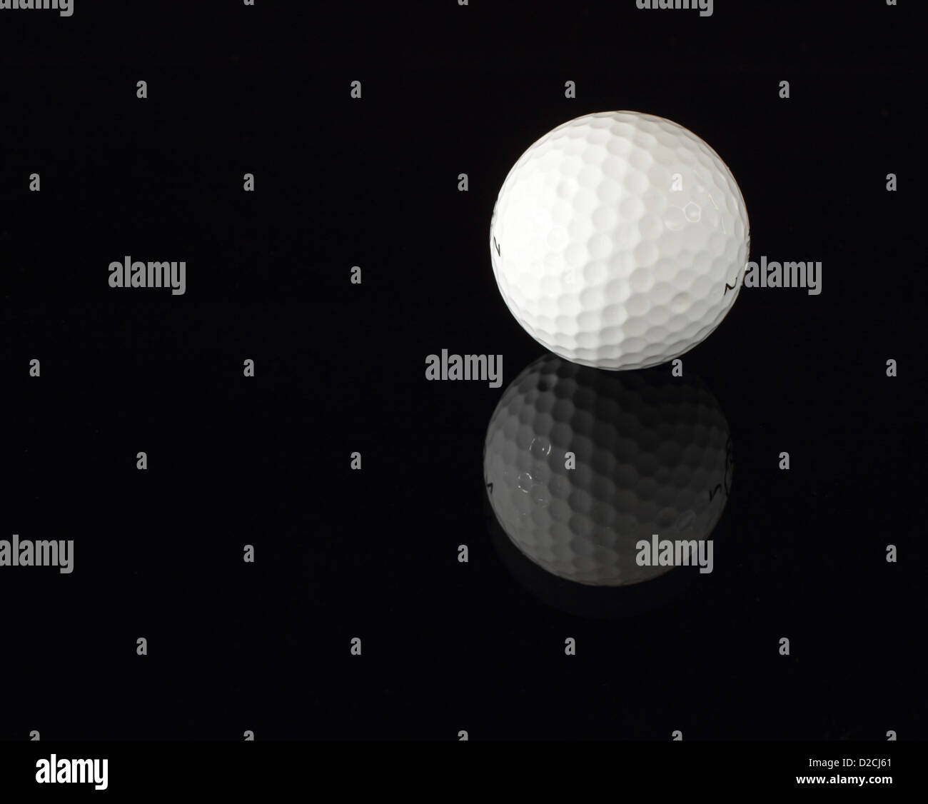 A golf ball reflecting on a black surface. Stock Photo
