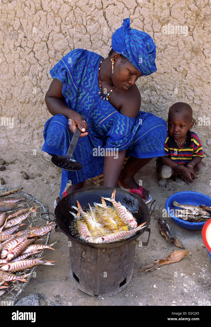 A woman selling freshly cooked fish at a market in Mali, West Africa. She is wearing a boubou - traditional robe dress. Stock Photo