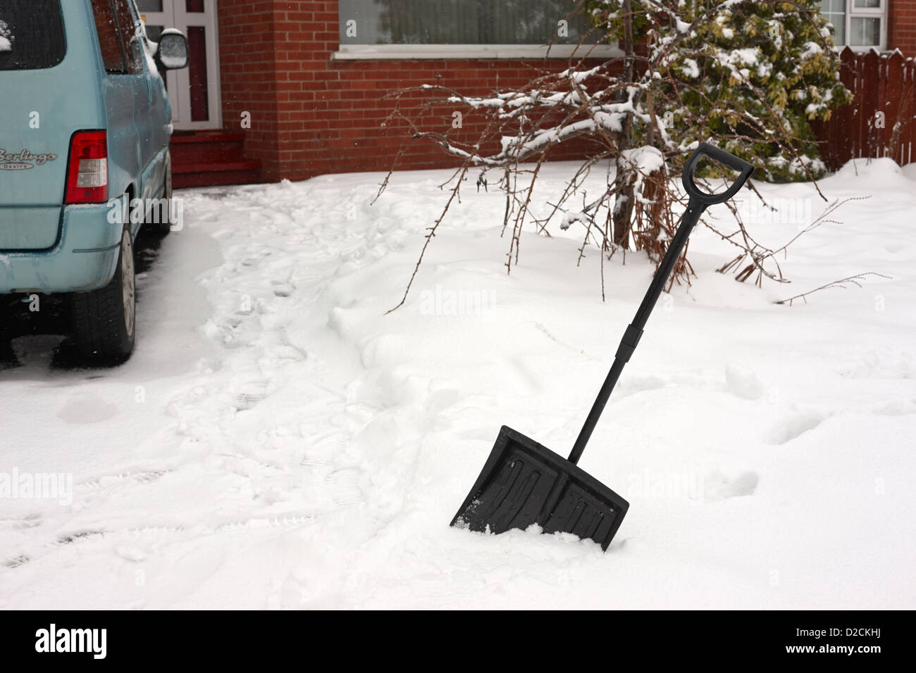 snow scoop shovel in deep snow clearing driveway during bad winter weather newtownabbey uk Stock