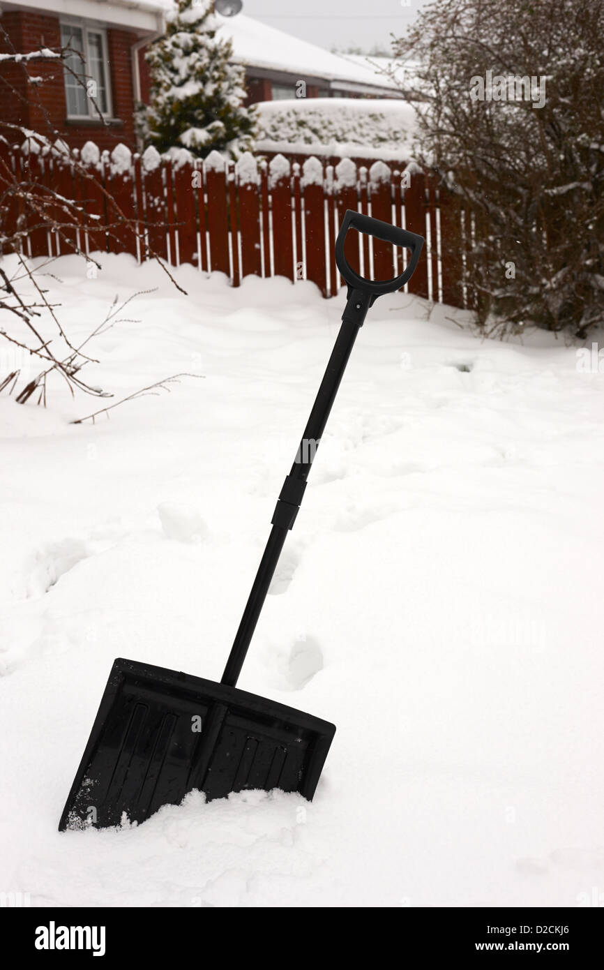snow scoop shovel in deep snow in garden during bad winter weather