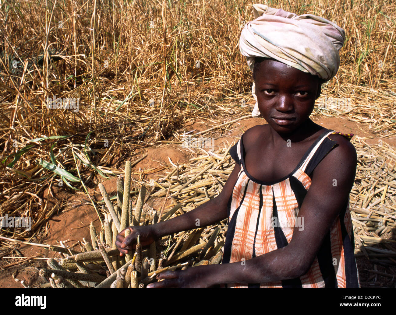 Young girl stands by some millet in Mali, West Africa. Stock Photo