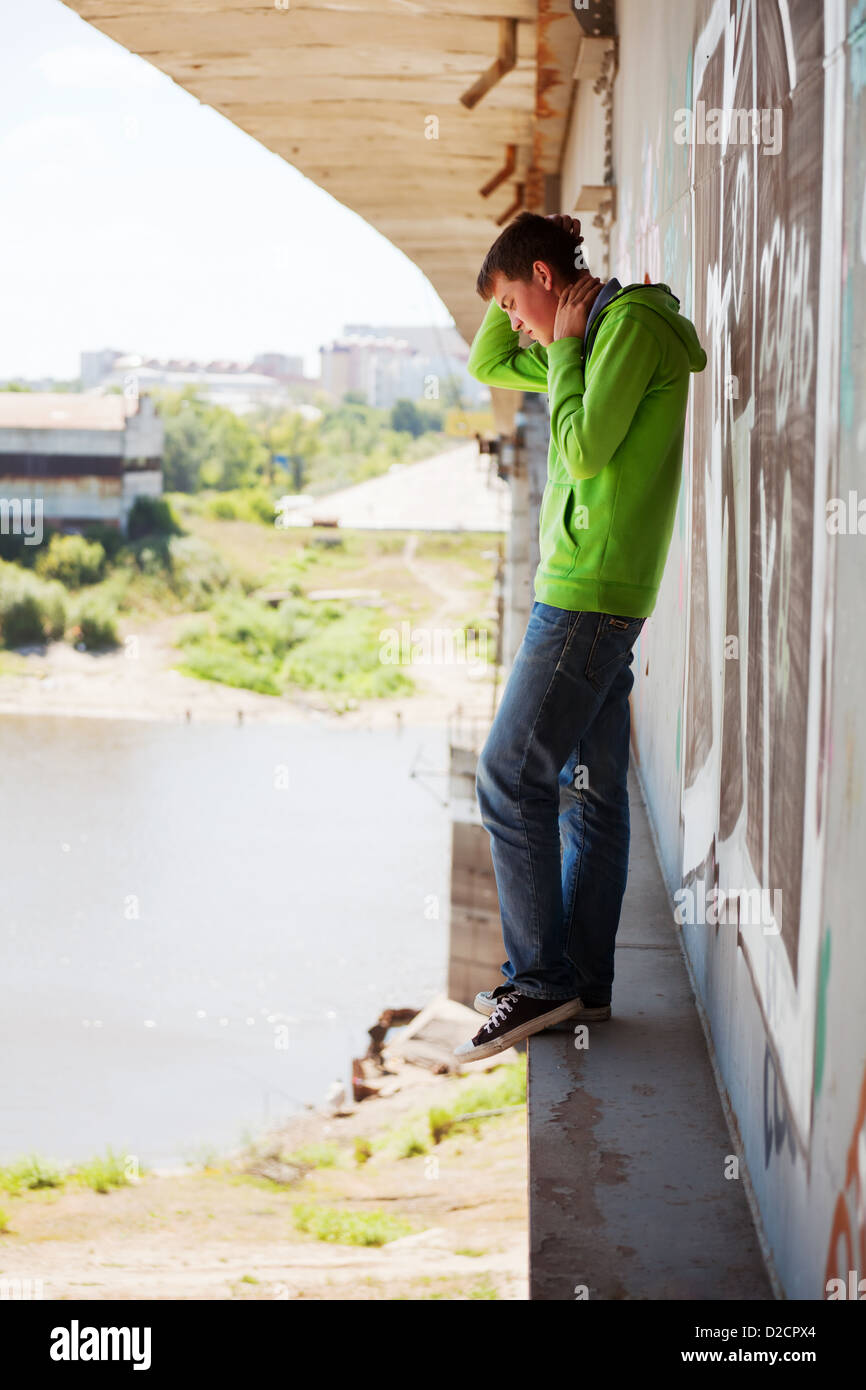 Young man in depression standing on the bridge Stock Photo