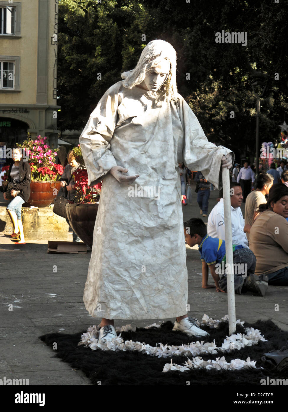 Mexican mime street performer in penitent sackcloth & ashes standing in flower garland in zocalo plaza Oaxaca de Juarez Mexico Stock Photo