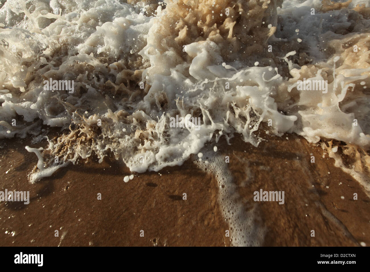 Detail of waves splashing on the edge of a sandy beach Stock Photo - Alamy