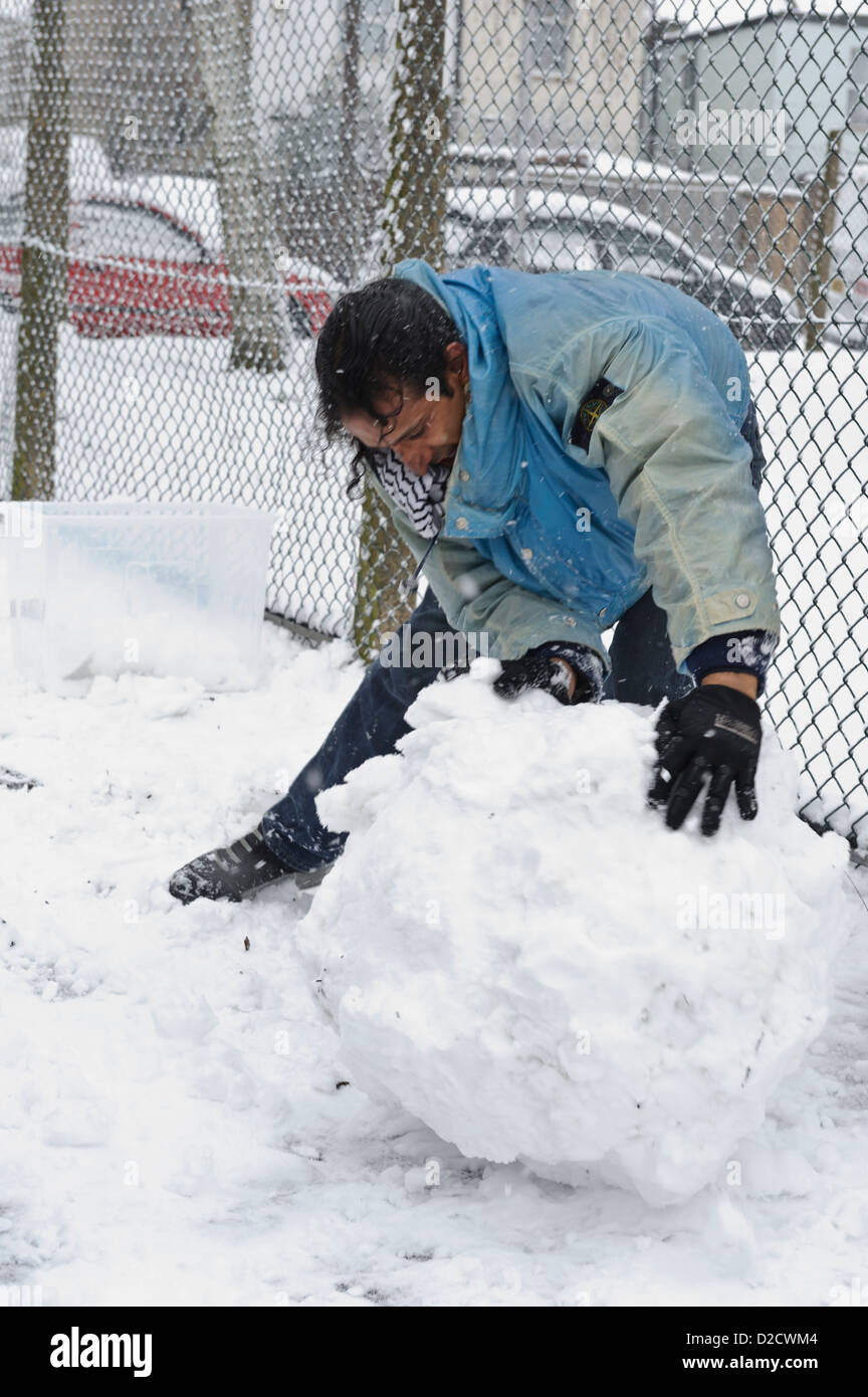 Man rolling snow to make snowman, Surrey, United Kingdom Stock Photo