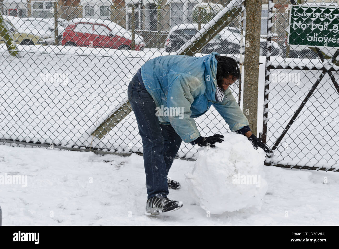 Man rolling snow to make snowman, Surrey, United Kingdom Stock Photo