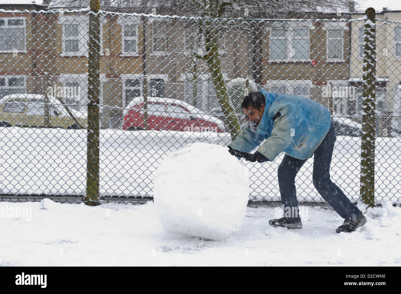 Man rolling snow to make snowman, Surrey, United Kingdom Stock Photo