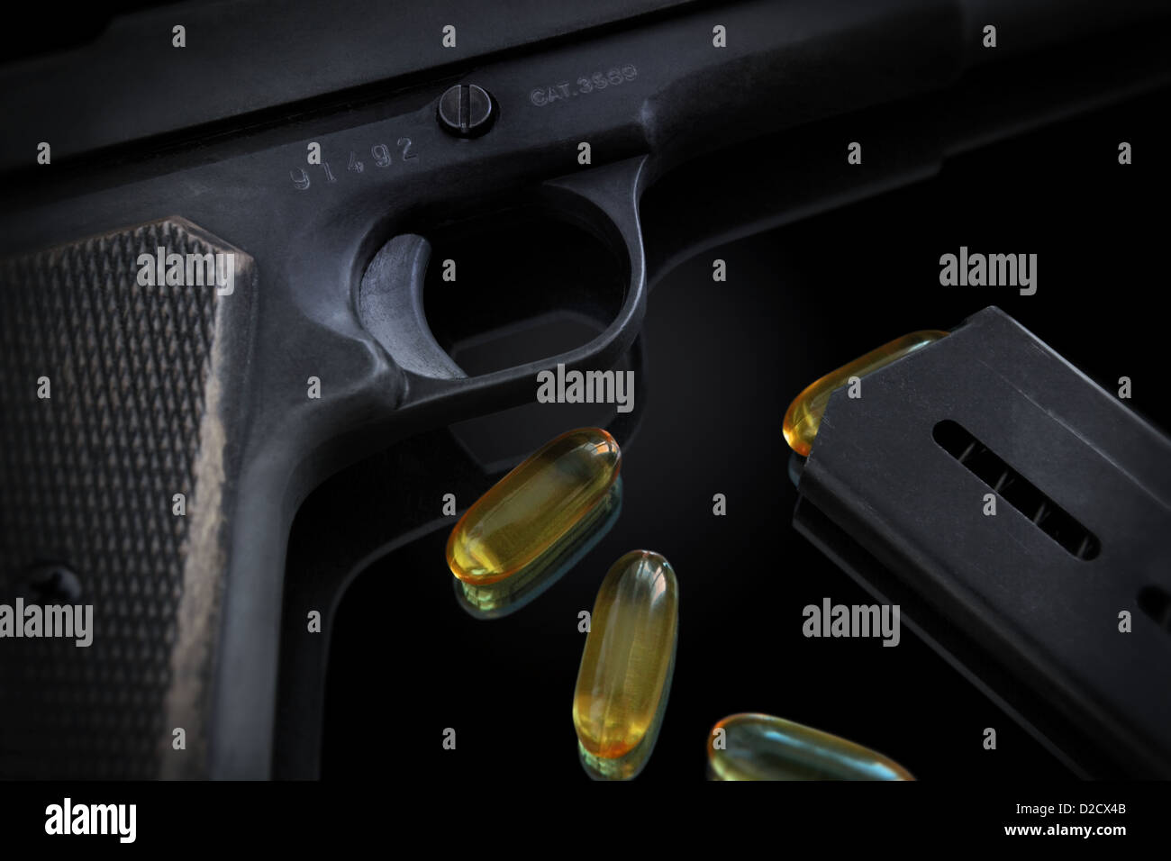 we see some details of a gun, the charger and some gel pills that are positioned to look like bullets. Low key. Stock Photo