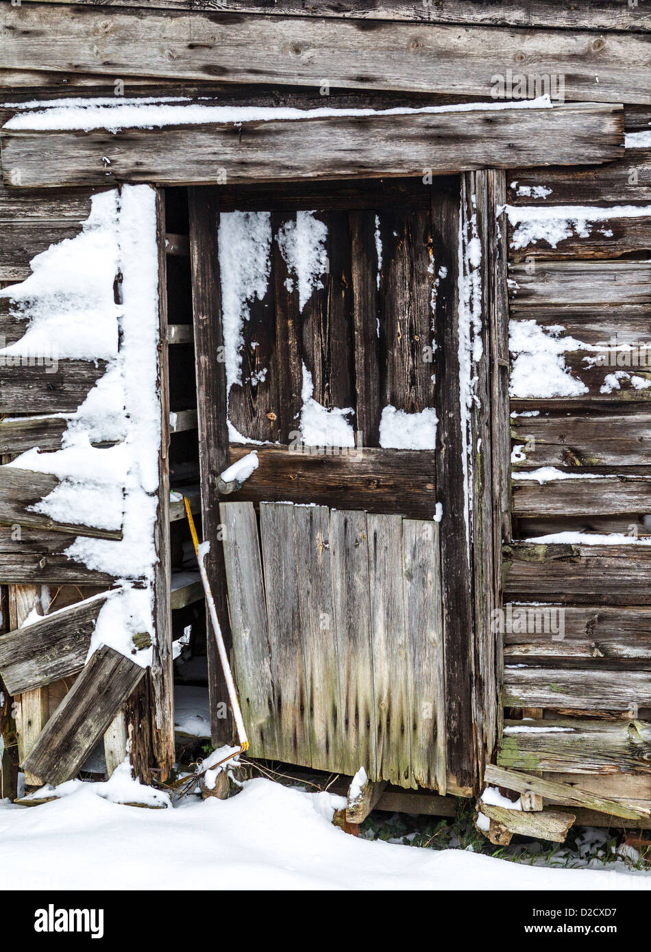 A rickety old door on a wooden shed in the snow Stock Photo