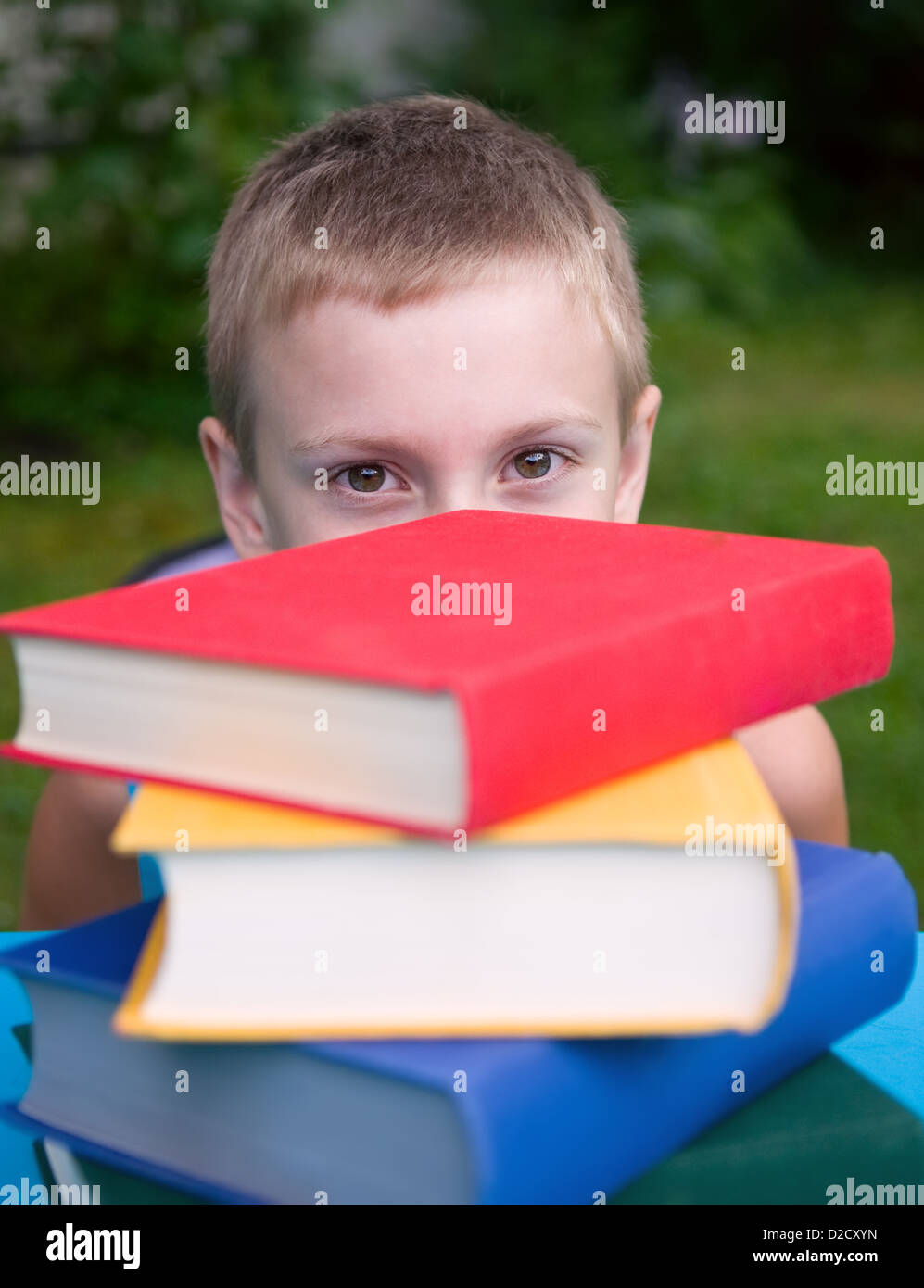 8-year schoolboy and stack of books outdoors Stock Photo - Alamy