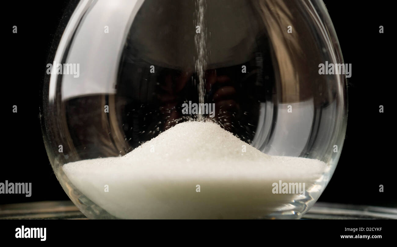 Sand Falls Down Through a Crystal Hour Glass sitting on the Table Top Stock Photo