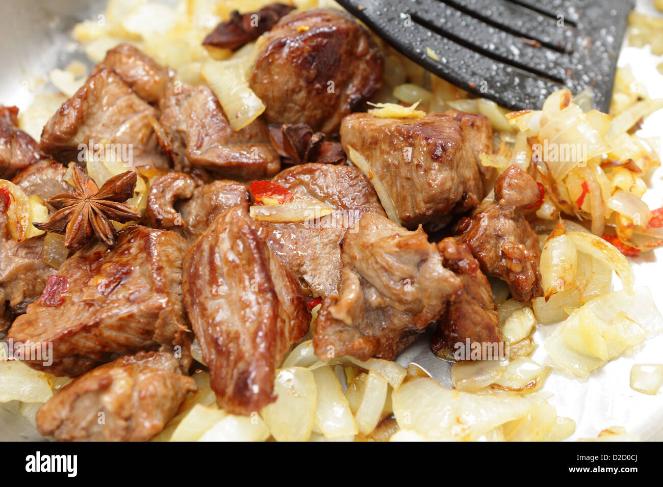 fried brown lamb cubes in a pan with onions, star anise, ginger, and garlic, part of cooking a far-eastern style curry Stock Photo