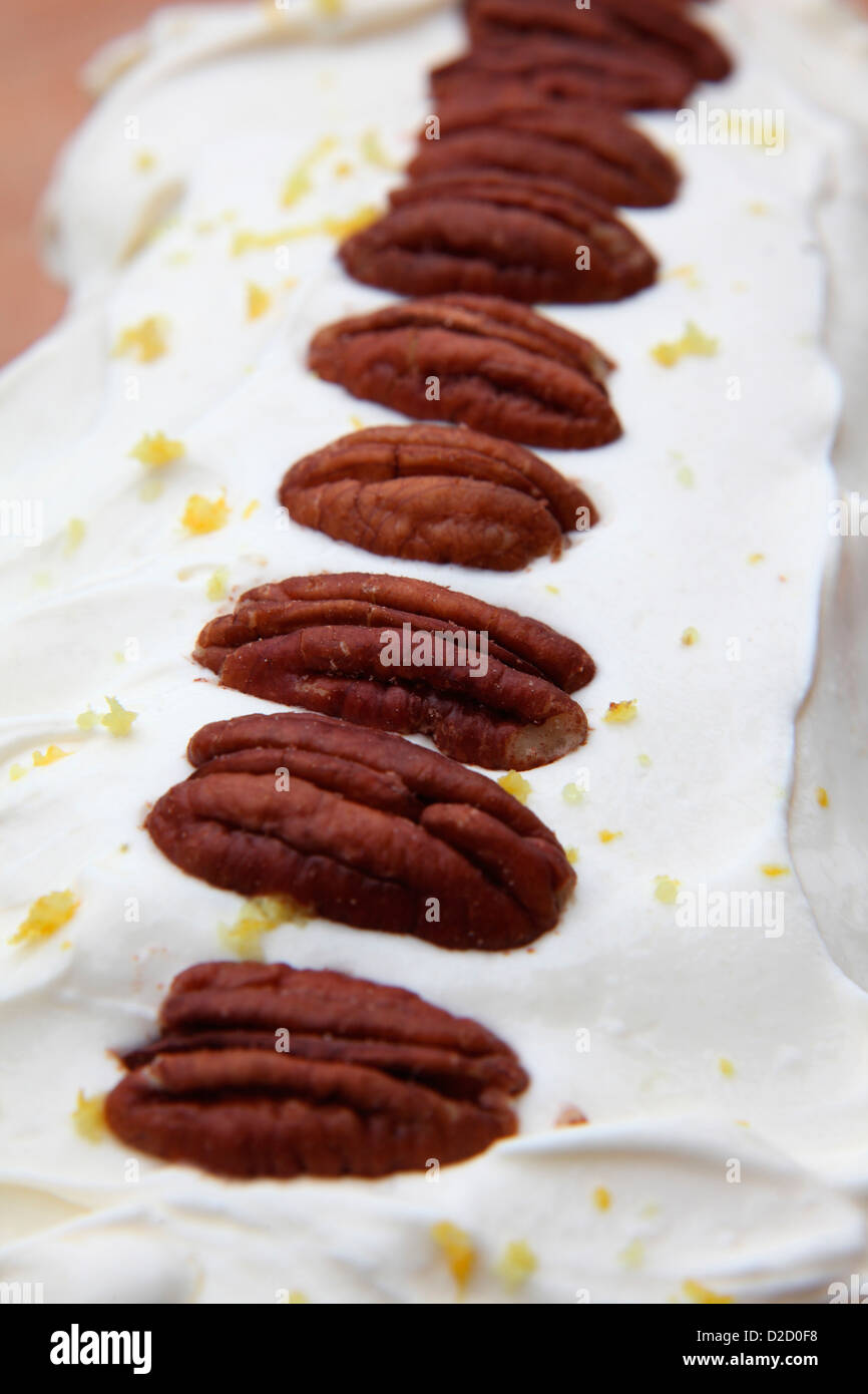 Carrot cake with cream cheese topping and decorated with pecan nuts