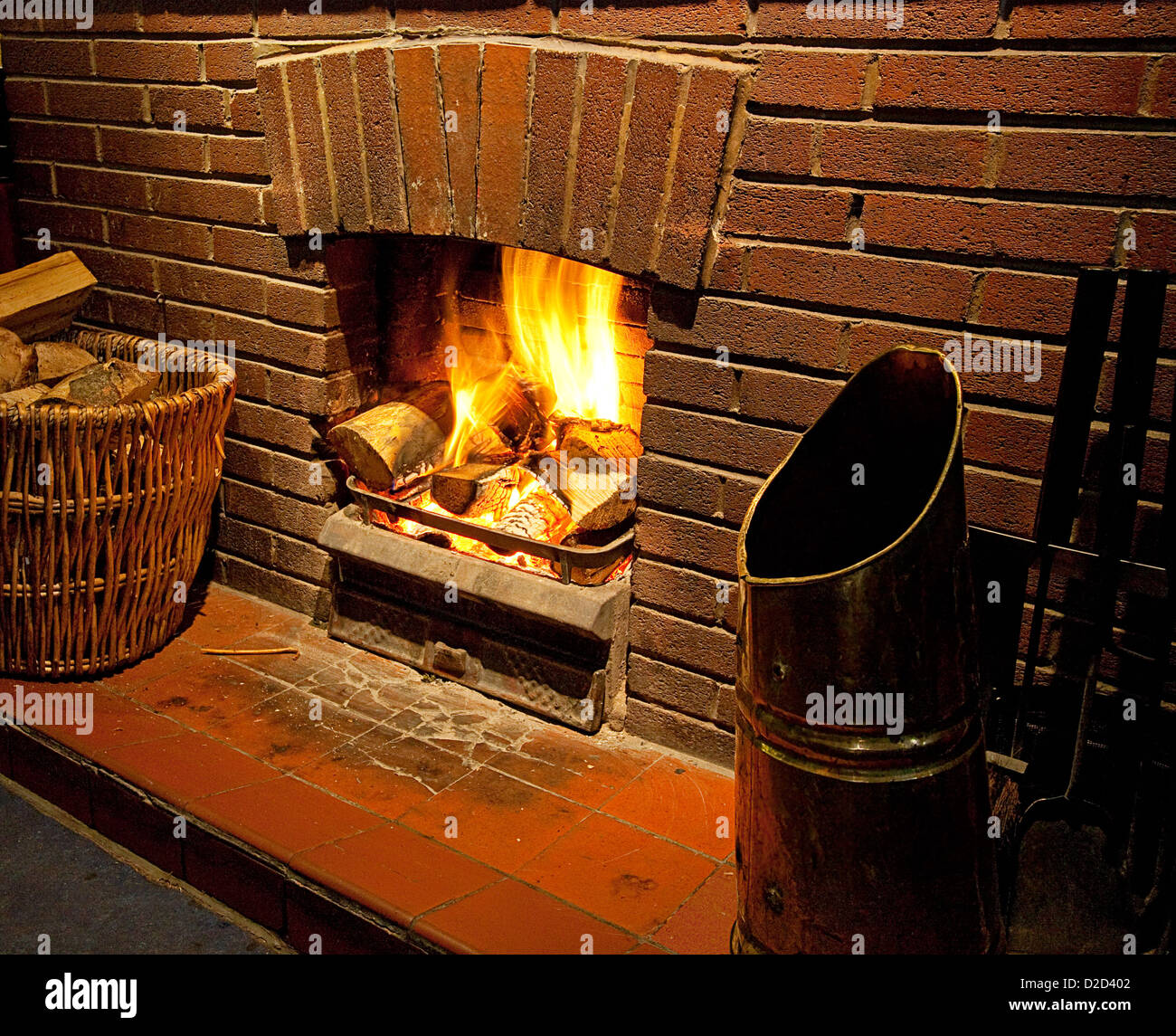Cosy bright Roaring log fire with brick surround glowing with flames going up chimney Stock Photo