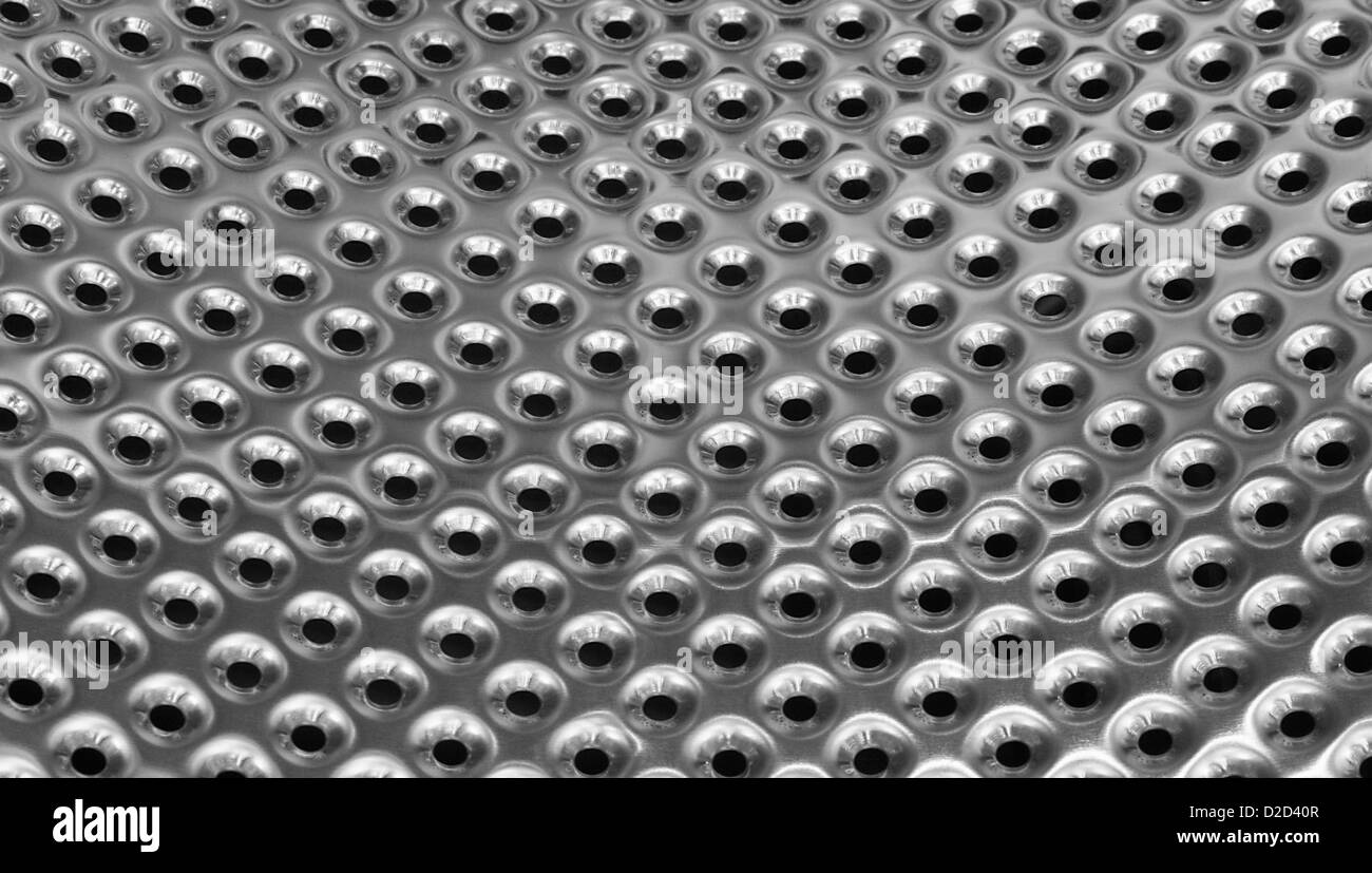 polished metal texture background with punched holes from inside of washing machine drum Stock Photo