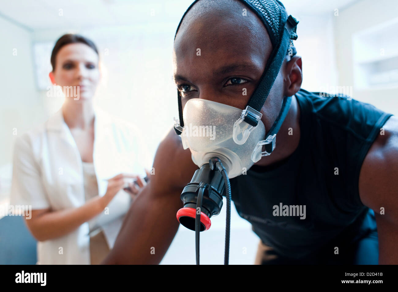 MODEL RELEASED Performance testing Athlete riding an exercise bike while his performance and oxygen consumption are measured Stock Photo