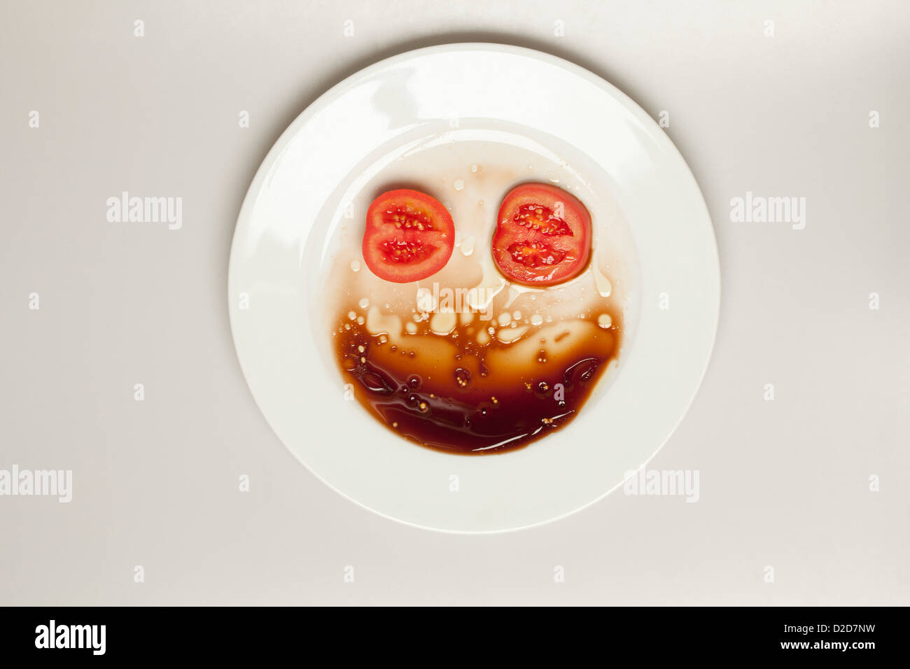 Abstract face made from tomato, plate and balsamic vinegar Stock Photo